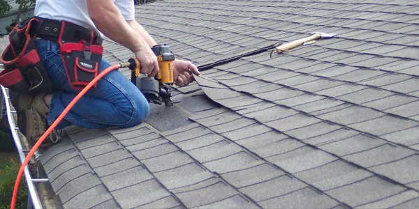 Professional roofer repairing damaged shingles