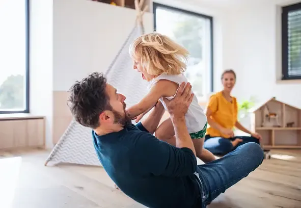 Father playing with daughter in a bright, minimalist home